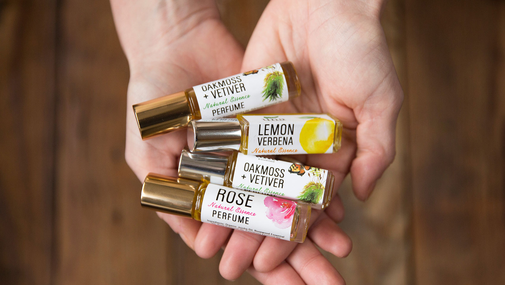 hands holding 4 different fragrance mini bottles from Una