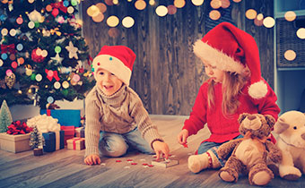 Little boy and little girls playing in front of a Christmas tree with gifts